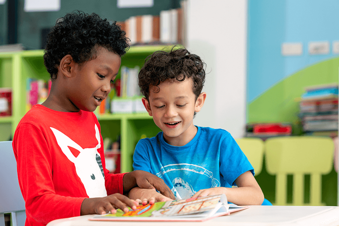 two elementary students reading a book