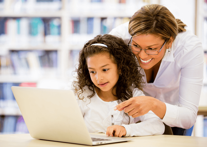 teacher assisting elementary student on a laptop