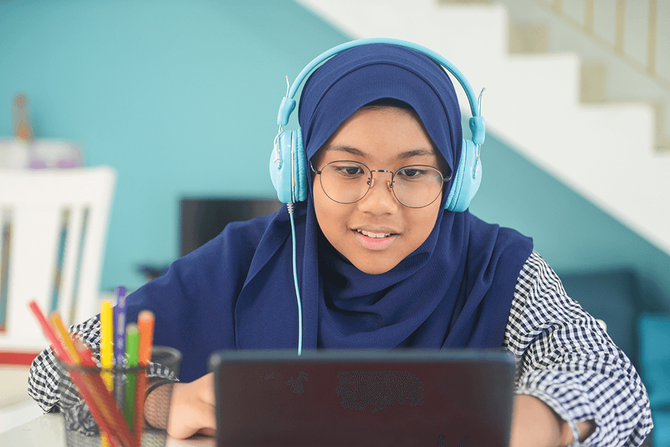 middle school student working on computer with head phones